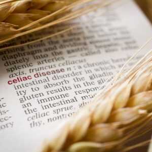 Celiac disease highlighted in a dictionary, with wheat laying on it.