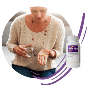 woman wearing sweater holds pills with glass of water